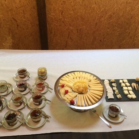 Auswahl an verschiedenen Käsesorten und Gläsern mit Konfitüre auf weißem Tisch.