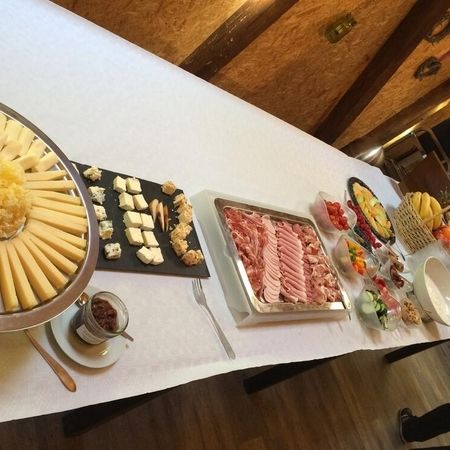 Reichhaltiges Buffet mit Käse, Wurst, Aufschnitt, Früchten und Dips auf weiß gedecktem Tisch.